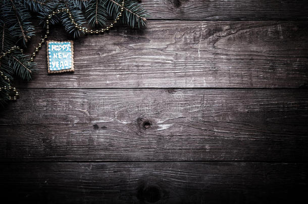 姜饼自制饼干与糖霜和圣诞树树枝在木制桌子或木板上作为背景。 新年主题。 色调