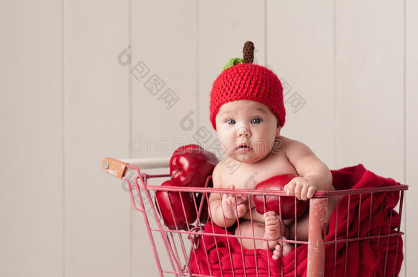 婴儿坐在购物车里戴着苹果帽