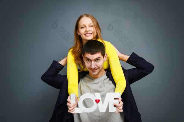 美丽的微笑的夫妇抱着爱的<strong>话语</strong>，站在灰色的背景上