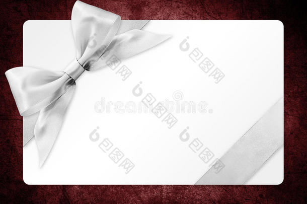 礼品卡与银丝带蝴蝶结隔离在红色背景上