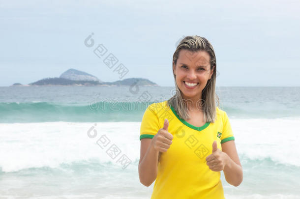 金发巴西体育迷在海滩上展示拇指