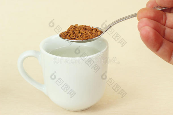 手拿着勺子，用速溶咖啡放在咖啡杯上