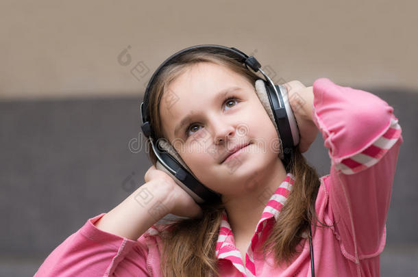 少女用大耳机听音乐，忧郁地抬头看