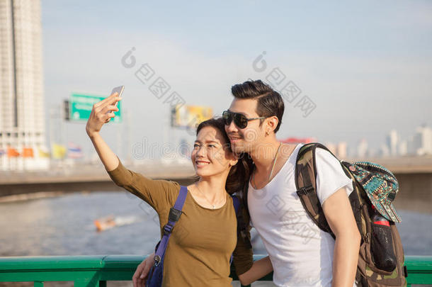 一对年轻的男人和女人在旅行地点用智能手机拍一张自拍照片