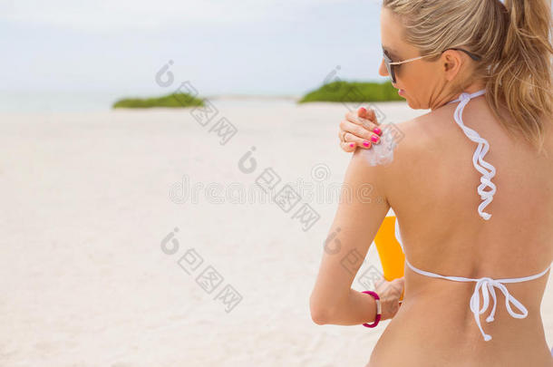 在海滩上涂防晒霜的女人