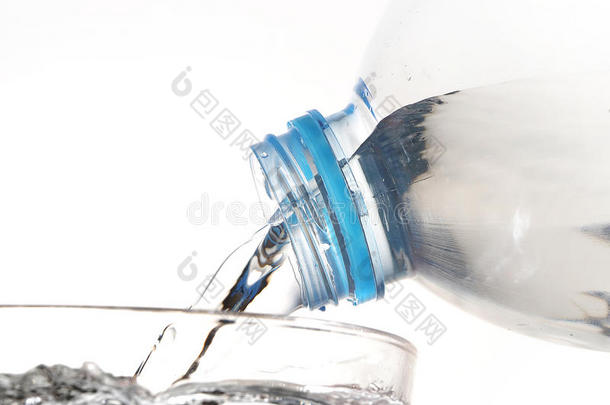 饮用水从瓶子里倒入白色背景的玻璃中