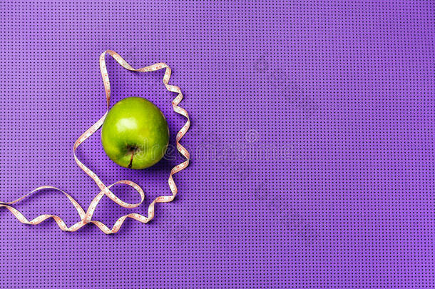 绿色苹果和测量带。 <strong>紫色瑜伽</strong>垫。