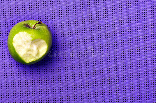紫色瑜伽垫上的绿色苹果。 愉快地健身。 爱去