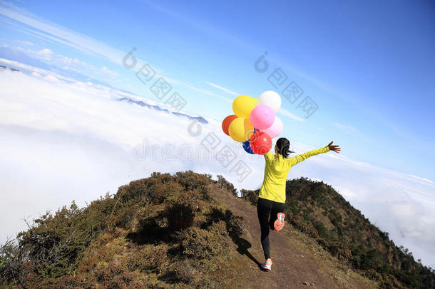 欢快的年轻女人带着气球在山上奔跑