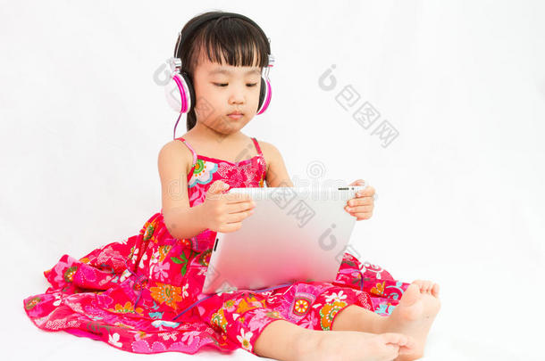 戴着耳机的中国小女孩拿着平板电脑