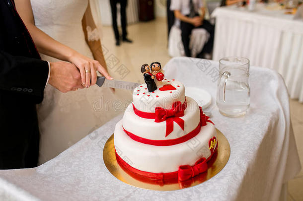 一对夫妇用红丝带和雕像切结婚蛋糕