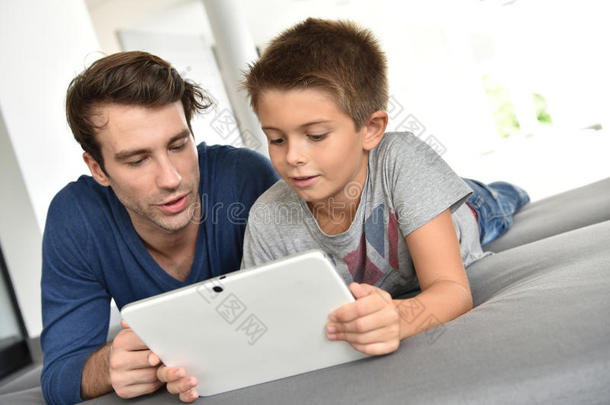 父亲和他的男孩在平板电脑上一起玩