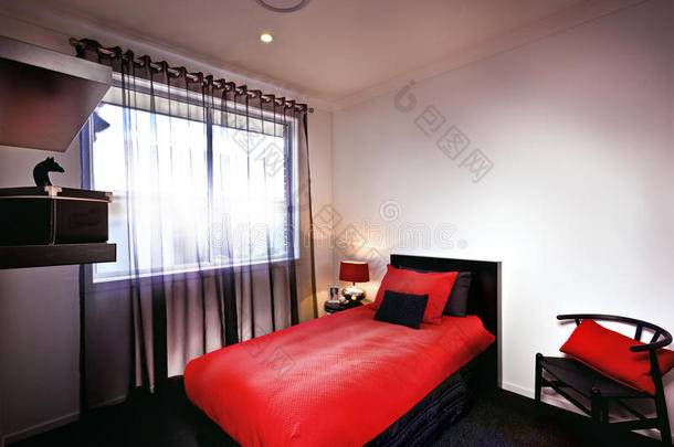 一个时尚的卧室，红色床单和垫子和枕头放在床上