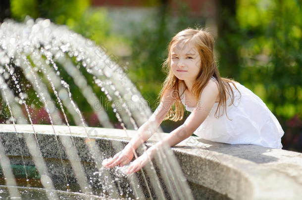 可爱的小女孩在炎热的夏天玩城市喷泉