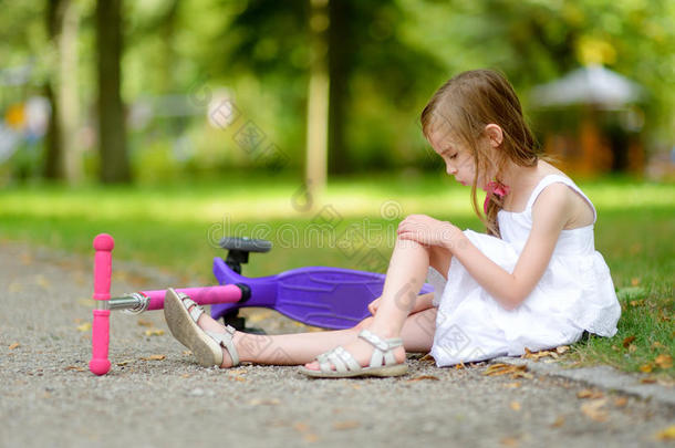 一个女孩骑着她的滑板车<strong>摔倒了</strong>