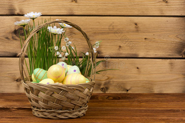 复活节装饰-篮子与鸡蛋，花在木制背景。