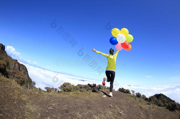 欢快的年轻女人带着气球在山上奔跑