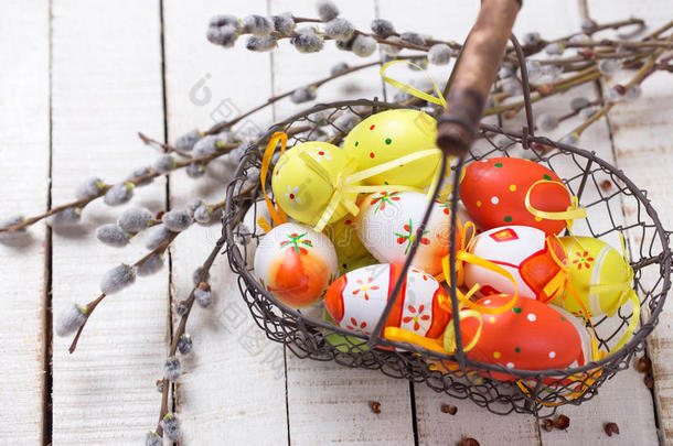篮子里有复活节鸡蛋和柳树枝木制背景上。