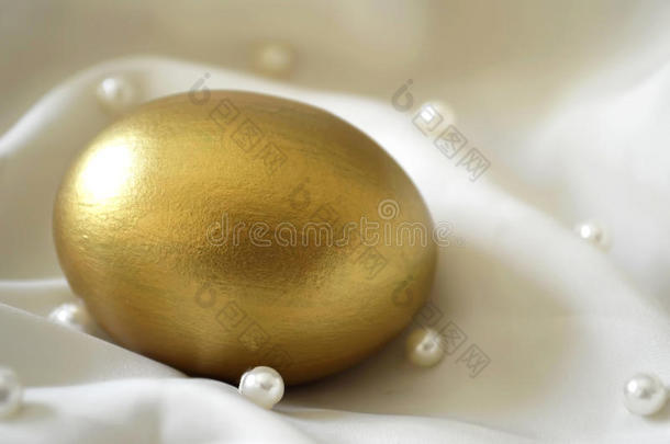 丝绸背景上的金蛋和珍珠