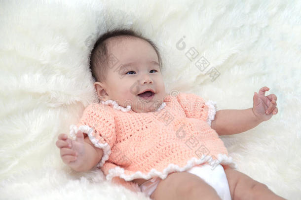 可爱的五个月的亚洲婴儿穿着橙色的衣服笑着