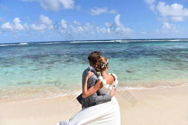 一对穿着婚纱的夫妇看着大海
