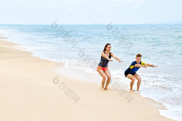 健身运动。 健康的夫妇<strong>蹲着</strong>，在海滩上锻炼