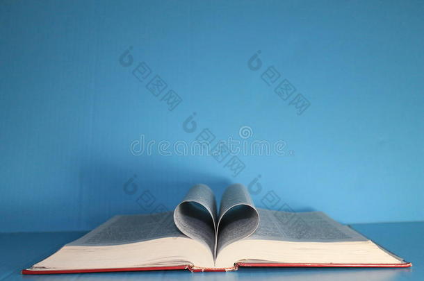 蓝色海报板上的圣经，页面折叠成心形