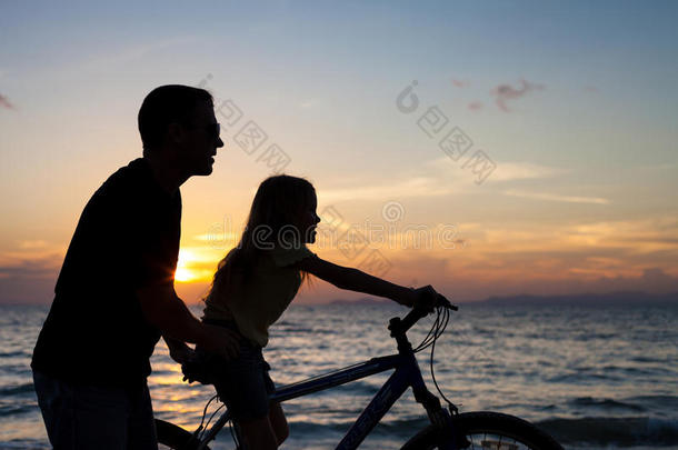 父亲和女儿在日落时在海滩上玩耍。