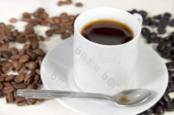 咖啡杯和茶匙放在咖啡豆旁边的茶托上