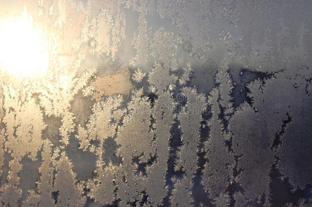 冰冻的窗户覆盖着冬天的霜花图案。