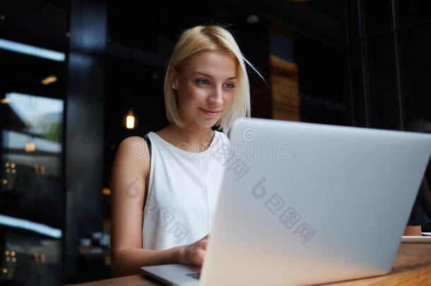 年轻漂亮的金发女学生在做功课时使用手提电脑，