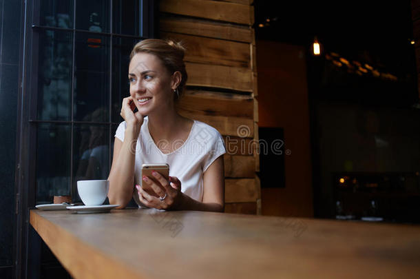 美丽的女人，可爱的微笑，拿着智能手机，坐在咖啡馆<strong>酒吧</strong>，在她的娱乐时间，