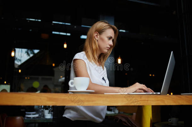 迷人的年轻白种女人在餐馆的咖啡休息时间用手提电脑工作，