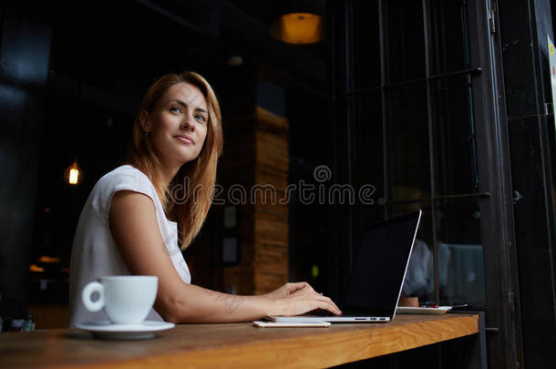 美丽的白种人女人在现代咖啡馆酒吧里坐着便携式上网本梦想着什么