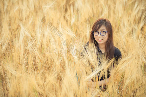 亚洲美丽的眼镜女人在大麦田