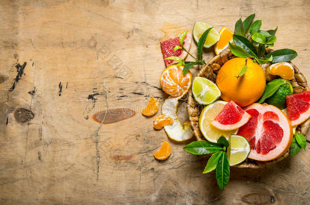 柑橘类水果-葡萄柚，橘子，橘子，柠檬，石灰在一个有叶子的篮子里。
