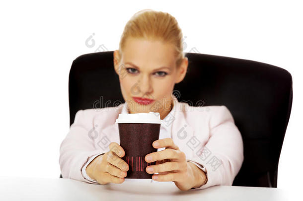 商务女士拿着纸杯里的咖啡坐在桌子后面