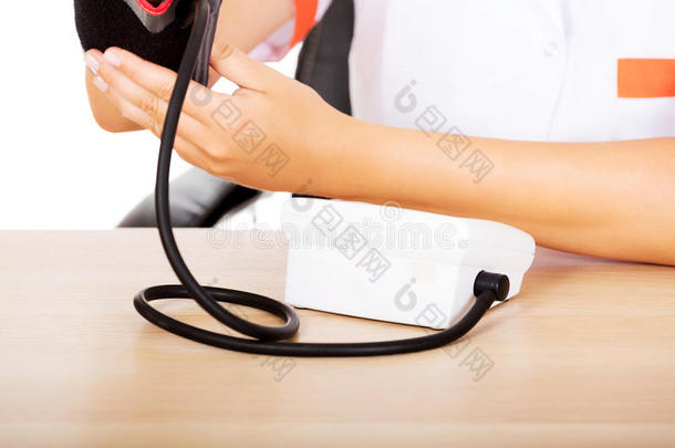 医生坐在桌子后面拿着<strong>血压计</strong>