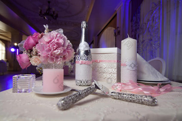 香槟，蜡烛和鲜花作为婚礼装饰品。 刀片和刀切蛋糕。