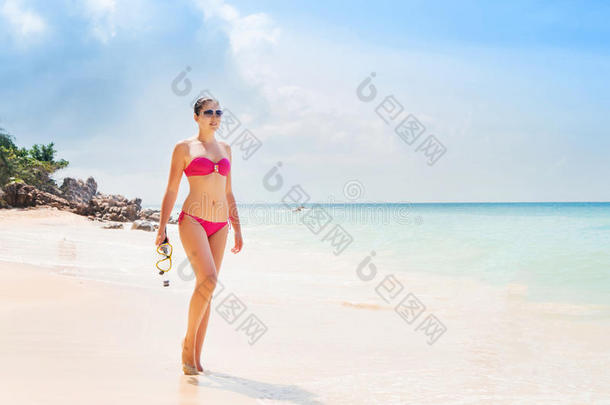 美丽的，穿着粉红色泳装的年轻女士戴着潜水面具在海滩上摆姿势