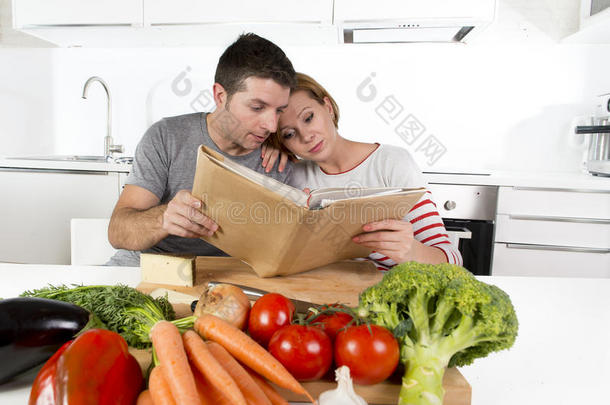 美国夫妇在家庭厨房工作，遵循<strong>食谱</strong>一起阅读<strong>食谱</strong>