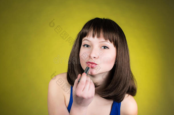 黑发女人涂红色口红。 女人把口红照在镜子里。 参加聚会前化妆准备好了