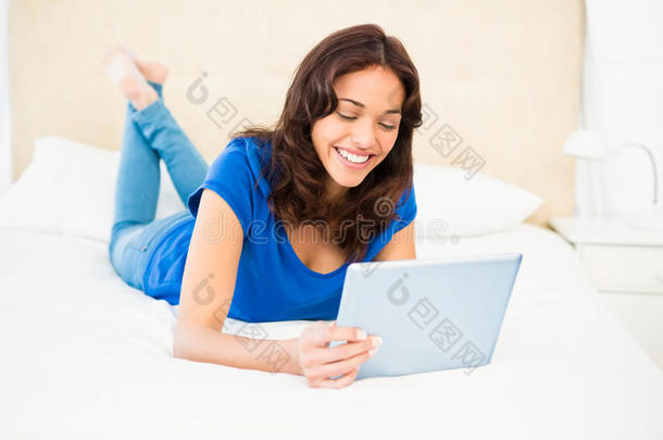 随意微笑的女人在<strong>床</strong>上使用笔记本电脑