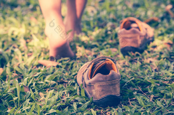 孩子脱鞋。 孩子的脚学会<strong>在草地上行走</strong>