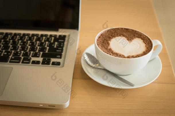 一杯白色杯子里的咖啡和桌子上的电脑桌面。