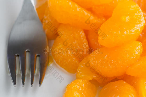 用叉子在盘子上装橘子罐头