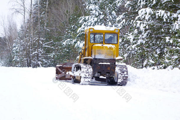 履带拖拉机平地机清洁森林道路上的雪。