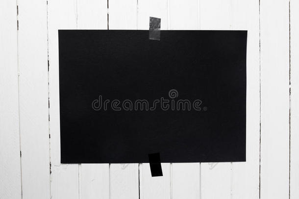 空白的<strong>黑色海报</strong>挂在白色木板墙上的胶带上。