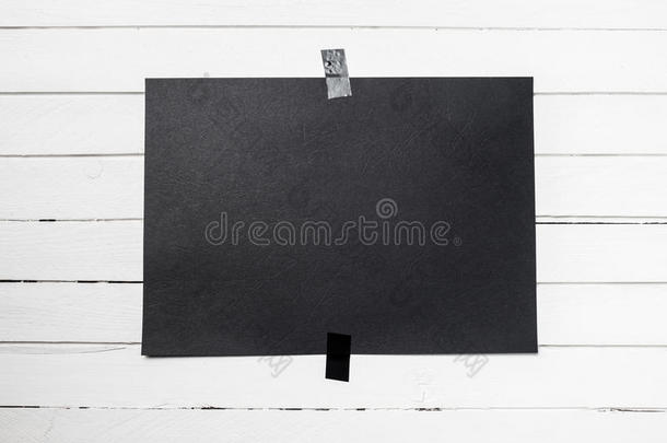 空白的<strong>黑色海报</strong>挂在白色木板墙上的胶带上。