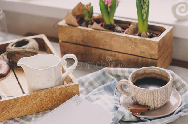 舒适的冬天早晨在家。 木制托盘上的咖啡、牛奶和巧克力。 花在<strong>背景</strong>上。 温<strong>暖</strong>的<strong>心</strong>情